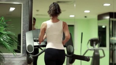 Spor salonunda egzersiz, koşu bandı kardiyo çalışması. Kadın spor salonunda koşu bandında yürüyor. Kadın spor salonunda antrenman yapıyor. Fiziksel aktivite kalorileri yakmaya yardımcı olur. Kadınlar spora gider. Kadın spor yapıyor.