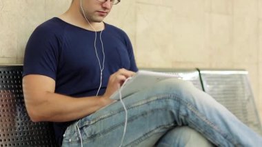 Tabletli adam metal bankta oturuyor. Yetişkin adam bankta oturur ve tablet bilgisayar kullanır. Tablet bilgisayarlı bir iş adamı. Tablet bilgisayarlı erkek