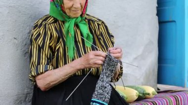 Son sınıf öğrencisi kadın bankta oturup yün çoraplar örüyor. Ukraynalı yaşlı kadın örgü örüyor. Yeşil başörtülü yaşlı kadın evinin yanındaki bankta oturup çorap örüyor. Eşarplı kadın çorap örüyor.
