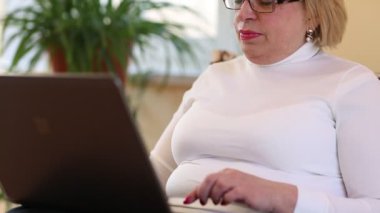 Kıdemli kadın dizüstü bilgisayarla iletişim kuruyor. Defterli bir kadın. Skype üzerinden iletişim. Dizüstü bilgisayarı olan iş kadını