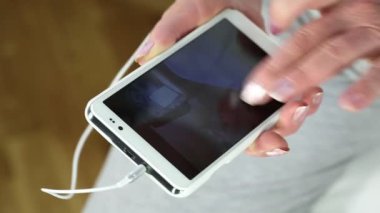 Kadın akıllı telefonuyla fotoğraflara bakıp göz gezdiriyor. Son sınıf öğrencilerinin eli beyaz akıllı telefon kullanıyor. Cep telefonu olan bir kadın.
