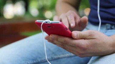 Adam fotoğraflara akıllı telefondan bakıyor. Adam el ele tutuşuyor, kırmızı cep telefonu. Kırmızı cep telefonlu erkek ellerine yakın çekim. Adam akıllı telefonuyla fotoğraflara bakıp göz gezdiriyor. Akıllı telefonu olan bir erkek.