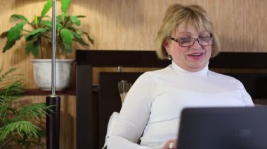 Kadın kıdemli laptop yolu ile iletişim kurar. Bir defter olan kadın. Skype üzerinden iletişim. Kadın defter var. İşkadını dizüstü bilgisayar ile