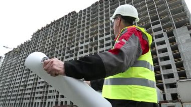 İnşaat alanında tasarım çizimleri olan beyaz başlıklı usta müteahhit. Bina denetimi. Proje alanında beyaz başlıklı işçi