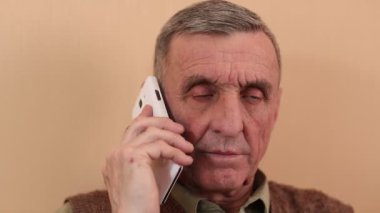 Akıllı telefonu olan yaşlı bir adam. Beyaz akıllı telefonlu son sınıf öğrencisi konuşuyor ve gülümsüyor. Yaşlı adam cep telefonuyla konuşuyor.