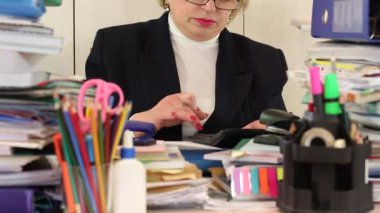 Kadın muhasebeci bardaklarda ve ticari kağıtları ile masada oturur, hesaplamak ve not edin. Hesap makinesi ve kalem olan kadın. Ticari belgeler, hesap makinesi ve kırmızı kalem ile arasında kadın muhasebeci