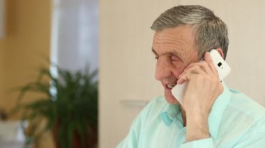 Beyaz cep telefonlu bir adam ofiste bir masada oturur ve brendi içer. Siyah gömlekli kıdemli adam masaya oturur, brendi içer ve akıllı telefondan iletişim kurar.