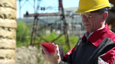 Elektrik santralinde kırmızı akıllı telefonu olan acil durum tamircisi. Isı istasyonunda akıllı telefondan anlayan bir elektrik mühendisi. Isı istasyonunda sarı şapkalı bir işçi. Kırmızı akıllı telefonu olan bir fabrika işçisi.