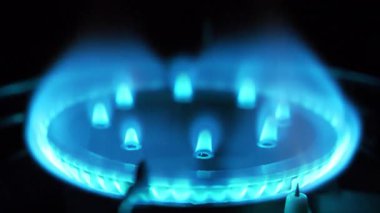 Mutfak gaz sobasından çıkan mavi gaz alevleri. Siyah arkaplanda yanan bir ateşle dönen gaz ocağı, yakın çekim