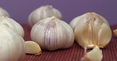 Sarımsak mor arka planda döner. Sarımsak, Allium sativum, Allium cinsindeki soğan çiçekli bitkiler. Sarımsak - sağlık için yararlı özelliklere sahip çok sağlıklı bir ürün