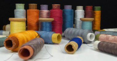 Siyah arkaplanda renkli iplikleri olan makaralar. Sinema 4K 60fps Uzaklaştırma Görüntüsü