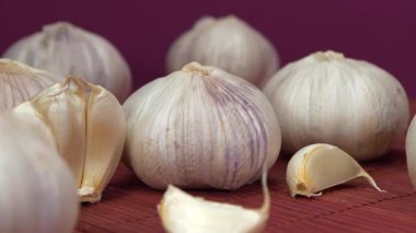 Sarımsak pembe arka planda döner. Sarımsak, Allium sativum, Allium cinsindeki soğan çiçekli bitkiler. Sarımsak - sağlık için yararlı özelliklere sahip çok sağlıklı bir ürün