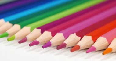 Yeni çok renkli güzel kalemler beyaz masanın üzerinde yatıyor.