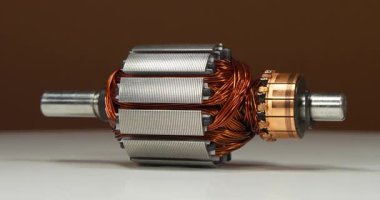 Küçük bir ev aletinin elektrikli motorundan bakır bobinli perküsyon masaj aleti. Kahverengi arka planda döner. Sinema 4K 60fps video