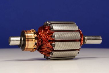 Koyu mavi arka planda küçük ev aletlerinden oluşan bakır bobinli elektrikli motor pervanesi.