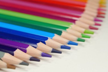 Yeni ahşap renkli kalemler, gökkuşağı renginde dizilmiş masa üzerinde yatıyor. Kalemler iyice açılmış.