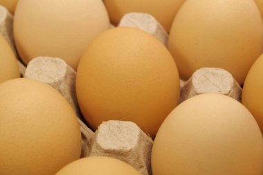 Tepside temiz sarı tavuk yumurtası, üst manzara. Koyu bej tavuk yumurtaları, yakın plan fotoğraf.