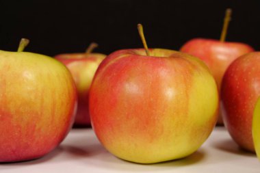 Olgun taze kırmızı, siyah arka planda sarı elmalar.