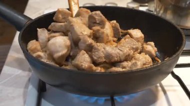 Kızarmış et. Aşçı et parçalarını gaz sobasında kızartma tavasında karıştırır.