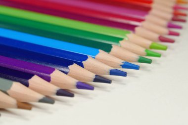 Yeni ahşap renkli kalemler, gökkuşağı renginde dizilmiş beyaz bir masada yatıyor. Kalemler iyice açılmış.