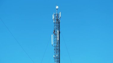 KYIV, UKRAINE, 27 Mart 2025: 2 işçi baz istasyonunda. Tamirciler yeni kablo ve ekipman kuruyor. İşçiler baz istasyonunu onarıyor. Mavi arka plandaki baz istasyonu. İşçiler, bakım personeli işte.