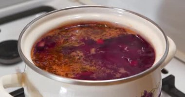 Ukrayna mutfağının ana yemeği. Ukrayna borsası gaz sobasında pişirilir. İlk yemekleri pişiriyorum. Ukrayna 'nın ulusal yemeği. Kırmızı Ukrayna borsası beyaz tencere içinde kaynıyor, yakınlaştırma videosu