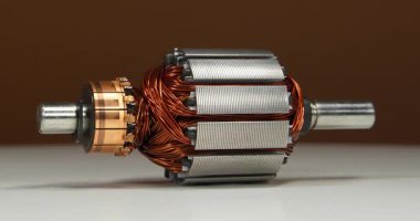 Küçük ev aletlerinden oluşan bakır bobinli elektrikli bir motorun armatür veya rotoru, yani perküsyon masajcıdan, beyaz masaya uzanır ve kahverengi arka planda döner.