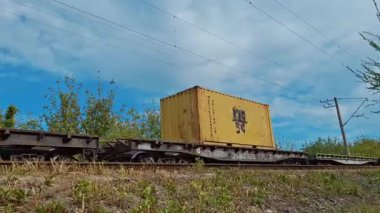 KYIV, UKRAINE, SEPTEMBER 27, 2025: Yük treni demiryolu boyunca hareket ediyor, konteynırları ve çeşitli üretimleri taşıyor. Sesli video