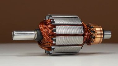 Kahverengi arka planda, perküsyon masajcısı olarak adlandırılan, küçük bir ev aletinin bakır bobinli elektrikli bir motorun armatür veya rotoru.