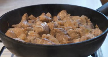 Kızarmış et. Soğanlı et parçaları, gaz ocağında tavada kızartılıyor. Kızartma tavası buharlaşıyor, yakın çekim yakınlaştırma videosu