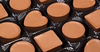 Pakette çikolatalı şekerler. Sevgililer Günü Hediyesi. Şekerler yuvarlak, kare ve kalp şeklinde. Kalp şeklinde olanlar da dahil olmak üzere farklı şekillerde lezzetli çikolata şekerlemeleri.