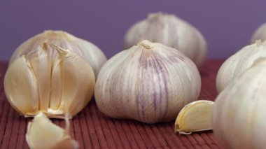 Birkaç sarımsak başı menekşe arka planda döner. Sarımsak, Allium sativum, Allium cinsindeki soğan çiçekli bitkiler. Sarımsak - sağlık için yararlı özelliklere sahip sağlıklı bir ürün