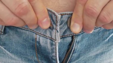 İnsan pantolonunu belinden ilikleyemez. Dar kot ve şişman göbek. Pantolon boyutu küçük ve uygun değil. Kollarını ve belini yakın çekim. Giysileri prova odasında deniyorum.