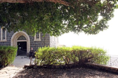 Bir Fransisken keşişi Aziz Peter Kilisesi 'nin önünde oturuyor, Celile Denizi, Tabgha, İsrail