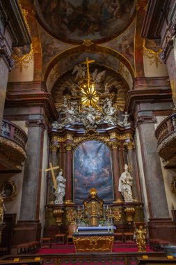Parlak ışık kaynağına sahip boyalı bir kubbenin altında heykel ve süslemelerle çevrili merkezi bir sunak ve bir haçla süslenmiş zengin bir kilise iç mimarisi..