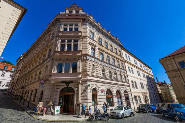 Geleneksel bir ön cephe ile bir köşe bina dekoratif ayrıntılar, çoklu pencereler, ve dik mavi gökyüzü karşısında duran insanlar ve araçlar sokak seviyesinde nüfus.