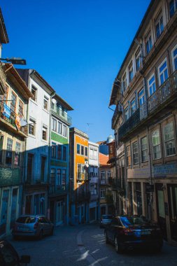 Geleneksel binalar ve uzak bir kilise kulesi tarafından çerçevelenmiş, hareketli şehir manzarasını gezen arabalar, tramvaylar ve yayalar ile tarihi bir şehirde yoğun bir Avrupa caddesi.