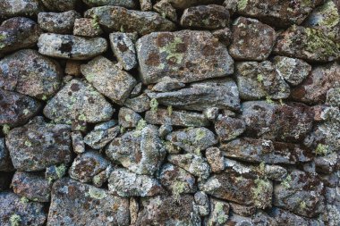 Düzensiz şekilli kayaların oluşturduğu taştan bir duvarın yakın çekim görüntüsü.