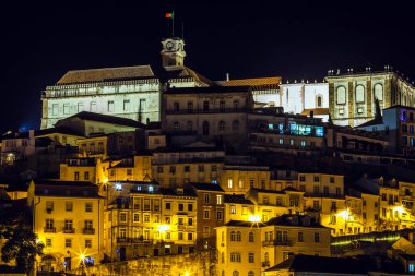 Bir tepenin üzerinde güzel aydınlatılmış tarihi bir bölge, katmanlı mimari ve sıcak ışıklar geleneksel binaların üzerine altın bir parıltı saçıyor.