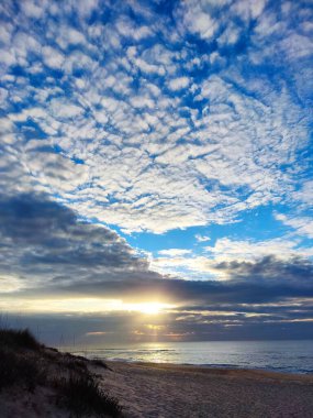 Güneşin doğuşunda çarpıcı bir kumsal sahnesi. Çarpıcı bir gökyüzü.