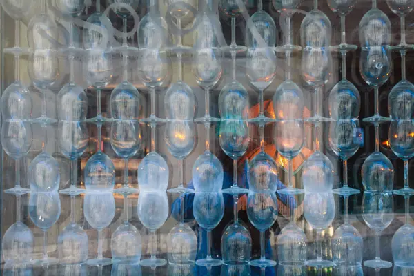 Yaratıcı ve soyut bir görsel efekt, saydam bardakların (muhtemelen şarap bardakları) çoklu katmanlarının tekrarlanan ızgara şablonu şeklinde istiflendiği veya düzenlendiği