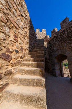 Kadim bir kalenin duvarları arasında yükselen taş bir merdiven, daha yüksek bir savaşa öncülük ediyor.