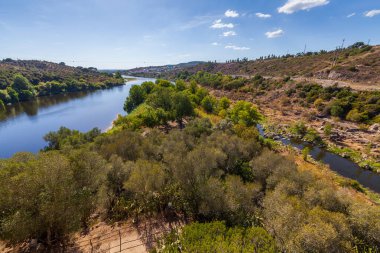 Bereketli ağaçlar ve çorak tepe arazileriyle çevrili kıvrımlı bir nehir..