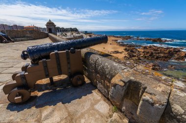Tarihi bir top okyanusa bakan taştan bir kale duvarına monte edildi. Arka planda açık mavi gökyüzü vardı.