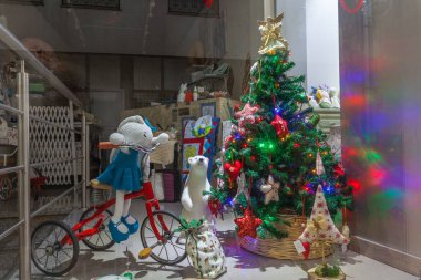 Süslü bir ağaç, oyuncaklar ve diğer şenlikli süslemelerin yer aldığı bir Noel vitrini.