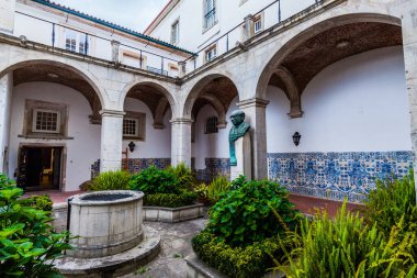 Kemerli yolları, merkezi bir kuyusu ve renkli döşemeleri olan sakin bir avlu.