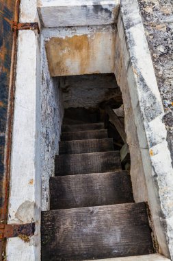 Dar ve loş bir merdiven gizemli bir yeraltı geçidine iniyor.