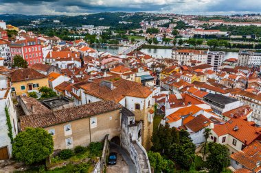 Portekiz 'in Coimbra kentinin panoramik manzarası, tarihi binaları, kırmızı kiremitli çatıları ve Mondego Nehri' nin şehirde dalgalanması.