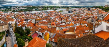 Portekiz 'in Coimbra kentinin panoramik manzarası, tarihi binaları, kırmızı kiremitli çatıları ve Mondego Nehri' nin şehirde dalgalanması.