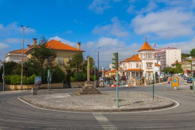 Portekiz, Coimbra 'da renkli binalar, merkezi bir haç ve açık mavi gökyüzü olan pitoresk bir sokak kavşağı.